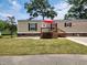 Tan mobile home with deck, red umbrella, and small yard at 818 Wayne St., North Myrtle Beach, SC 29582