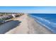 Wide sandy beach alongside a row of colorful beach homes and a pier in the distance at 2022 N Waccamaw Dr., Garden City Beach, SC 29576