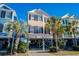 Charming raised beach home featuring a colorful exterior, black shutters, and palm trees at 2022 N Waccamaw Dr., Garden City Beach, SC 29576