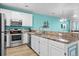 Modern kitchen with stainless steel appliances, white cabinets, tile countertops, and ocean view at 2022 N Waccamaw Dr., Garden City Beach, SC 29576