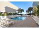 Community pool area featuring a pool, white picket fence, lounge chairs and palm trees on brick patio at 2022 N Waccamaw Dr., Garden City Beach, SC 29576