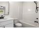 A bright, modern bathroom features a shower-tub combo, and sleek, dark hardware that accents the vanity at 2428 Park St., North Myrtle Beach, SC 29582