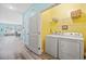 Laundry room with white washer and dryer, wire shelving, and bright yellow walls at 731 Yokley Ct., Surfside Beach, SC 29575