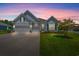 Charming gray home featuring a two-car garage, lovely landscaping, and a well-manicured lawn during twilight at 10 Grace Bay Ct., Pawleys Island, SC 29585