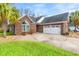 This is an inviting brick home with a two-car garage and well-maintained landscaping, set against a blue sky at 113 Preservation Dr., Myrtle Beach, SC 29572