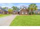 Charming brick home featuring a well-manicured lawn and palm trees lining the driveway, enhancing curb appeal at 113 Preservation Dr., Myrtle Beach, SC 29572