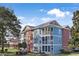 Multi-story building with blue and orange exterior, screened porches, and landscaping at 4641 Lightkeepers Way # 3A, Little River, SC 29566