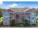 Two-story building with blue and orange exterior, featuring staircases and landscaping at 4641 Lightkeepers Way # 3A, Little River, SC 29566