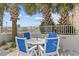 Inviting patio featuring a table with blue chairs, perfect for enjoying outdoor dining with picturesque views and swaying palm trees at 5511 N Ocean Blvd. # 302, Myrtle Beach, SC 29577