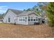 Back exterior view of a home showing a well-maintained yard and structure with a sunroom at 6716 Wisteria Dr., Myrtle Beach, SC 29588