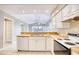 Well-lit kitchen featuring white cabinets, tile flooring, and view into adjacent living area at 677 Tupelo Ln. # 301, Longs, SC 29568
