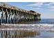 Wooden pier stretching out into ocean with waves crashing onto a sandy beach at 1209 Peyton Ct., Myrtle Beach, SC 29588
