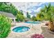 Community pool area featuring a hot tub, in-ground pool, lounge chairs, tables, and mature landscaping at 1209 Peyton Ct., Myrtle Beach, SC 29588