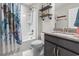 Well-lit bathroom with a shower-tub combo, stylish vanity, and decorative shelving for storage and display at 2450 Craven Dr., Myrtle Beach, SC 29579