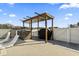Outdoor grilling area with a stone-covered island, grill, covered trellis, and an adjacent white privacy fence at 400 Dog Pen Ct., Myrtle Beach, SC 29579
