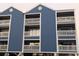 Blue condominium building featuring multi-level balconies, white railings, and elevated parking for a coastal design at 4305 N Ocean Blvd. # 205, North Myrtle Beach, SC 29582