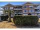 Multi-story condo complex with manicured landscaping, balconies, and private entrances at 4609 Lightkeepers Way # 11J, Little River, SC 29566