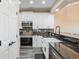 Well-lit kitchen boasts white cabinets, stainless steel appliances, farmhouse sink, and sleek black countertops for a modern look at 4609 Lightkeepers Way # 11J, Little River, SC 29566