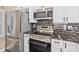 Kitchen with stainless steel appliances, white cabinets, and a striking black marble backsplash and countertops at 4609 Lightkeepers Way # 11J, Little River, SC 29566
