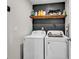 A functional laundry room with white appliances, a rustic shelf, and a dark accent wall at 589 Talisman Trail, Longs, SC 29568