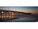Picturesque pier stretching into the ocean at sunset, reflecting orange light off the sand at 718 Isle Verde Dr, Myrtle Beach, SC 29579
