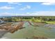 Expansive aerial view showcasing the marsh transitioning to a golf course surrounded by lush green trees and distant high-rise buildings at 9547 Edgerton Dr. # 606, Myrtle Beach, SC 29572
