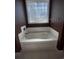 Close-up of a soaking tub with tile surround and a glass block window at 1501 Brighton Ln., Longs, SC 29568