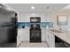 Modern kitchen with white cabinetry, black appliances, and eye-catching blue backsplash at 2106 N Ocean Bl N Ocean Blvd. # 211, Myrtle Beach, SC 29577