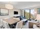 Bright living area featuring a dining table, sofa, TV, and balcony access overlooking the ocean and lush greenery at 2106 N Ocean Bl N Ocean Blvd. # 211, Myrtle Beach, SC 29577