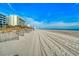 Bright beach view showing the sand, tire tracks, condo buildings, and a bright blue sky at 1207 S Ocean Blvd. # 20701, Myrtle Beach, SC 29577