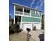 Two-story home featuring a green exterior, a white balcony, and a two-car garage with white doors at 4714 Woodland St., North Myrtle Beach, SC 29582