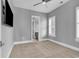 Neutral bedroom with carpet flooring, large window, plantation shutters, and an entry door to a bathroom at 5960 Bolsena Place, Myrtle Beach, SC 29577