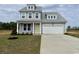 Charming two-story home featuring a yellow front door, a two-car garage, and a well-manicured lawn at 140 Joyce Dr, Longs, SC 29568