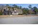 Charming home with stone and siding exterior, complemented by mature landscaping, palm trees, and a pool at 261 Marsh Tacky Loop, Myrtle Beach, SC 29588