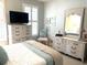 Bright bedroom featuring white furnishings, a large TV, and a comfortable bed with elegant bedding at 414 Grand Cypress Way, Murrells Inlet, SC 29576