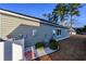 Exterior view of the home featuring a modern tankless hot water heater, gray siding, and white rock landscaping at 440 Craigflower Ct., Longs, SC 29568