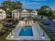 Aerial view of a community pool with condos, parking, and lush landscaping on a sunny day at 4459 Turtle Ln. # 3D, Little River, SC 29566