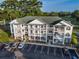 Three-story condo building featuring a green roof, white balconies, brick accents, and ample parking at 4459 Turtle Ln. # 3D, Little River, SC 29566
