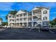 Three-story condo building with white balconies, brick accents, and lush landscaping on a sunny day at 4459 Turtle Ln. # 3D, Little River, SC 29566