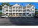 Three-story condo building with white balconies and brick accents surrounded by a well-maintained parking lot at 4459 Turtle Ln. # 3D, Little River, SC 29566