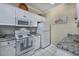 Galley kitchen featuring white appliances, granite countertops, white tile flooring, and stylish backsplash at 4459 Turtle Ln. # 3D, Little River, SC 29566