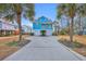 Two-story light blue house with a long driveway and palm trees at 74 Marsh Point Dr., Pawleys Island, SC 29585