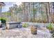 Backyard patio with a hot tub, table, and seating, surrounded by a white picket fence and dense trees for privacy at 128 Belclare Way, Longs, SC 29568