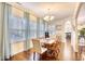 Bright dining room with hardwood floors, chandelier, and large windows with light blue curtains at 128 Belclare Way, Longs, SC 29568