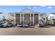 Three-story condo complex showing brick facade, white pillars and staircases on a sunny day at 136 Birch N Coppice Dr. # 11, Surfside Beach, SC 29575