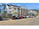 Condo complex with white pillars, brick facade, staircases and parking on a sunny day at 136 Birch N Coppice Dr. # 11, Surfside Beach, SC 29575