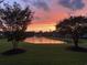 Picturesque sunset view of a pond with a fountain surrounded by lush greenery at 212 Minnow Ln., Murrells Inlet, SC 29576