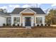 Modern farmhouse exterior features a gray-toned shingle roof, a dark gray front door, and a stylish wood beam accent at 270 Russ Rd., Loris, SC 29569