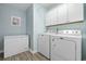 Well-lit laundry room featuring appliances and overhead cabinets for ample storage at 3713 Park Pointe Ave., Little River, SC 29566