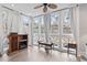 Bright sun room with a ceiling fan, fireplace, and multiple windows with white curtains at 4396 Baldwin Ave. # 94, Little River, SC 29566
